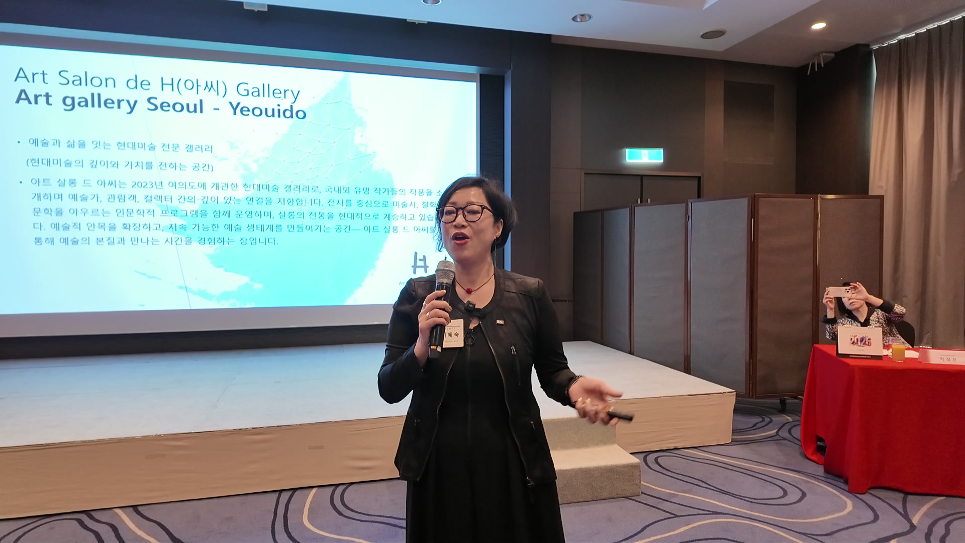 BNI 성동 포레스트 챕터 피처 발표에서 이혜숙 대표가 아트살롱드아씨 갤러리를 소개하는 화면 앞에 서 있다